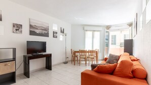 A modern living room with a TV, a dining table, and a sofa. - Happyfew Palais des arts (Nice)