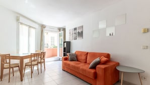 A living room with a sofa, a dining table with chairs, and a small side table. - Happyfew Palais des arts (Nice)