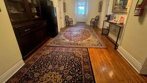 A hallway with a patterned rug, wooden cabinets, and a fire extinguisher on the wall.