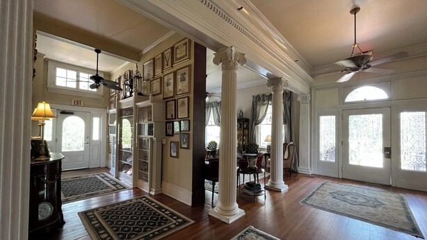 A spacious foyer with high ceilings, large windows, and a grand staircase.