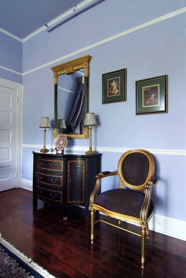 A room with a dark wooden dresser, a gold-framed chair, and two framed pictures on the wall.
