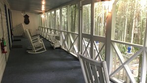 Eine überdachte Veranda mit weißen Schaukelstühlen und einem Feuerlöscher an der Wand.
