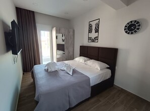 Una cama bien hecha con sábanas blancas, un cabecero marrón y un reloj de pared.