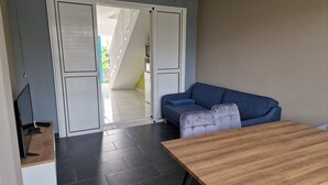 Ein modernes Wohnzimmer mit einem Holztisch, einem blauen Sofa und einem Fernseher auf einem Standfuß.