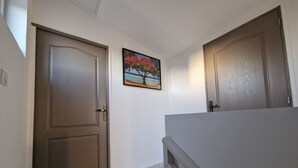 Ein Flur mit zwei Holztüren, einem Fliesenboden und einem gerahmten Bild an der Wand.