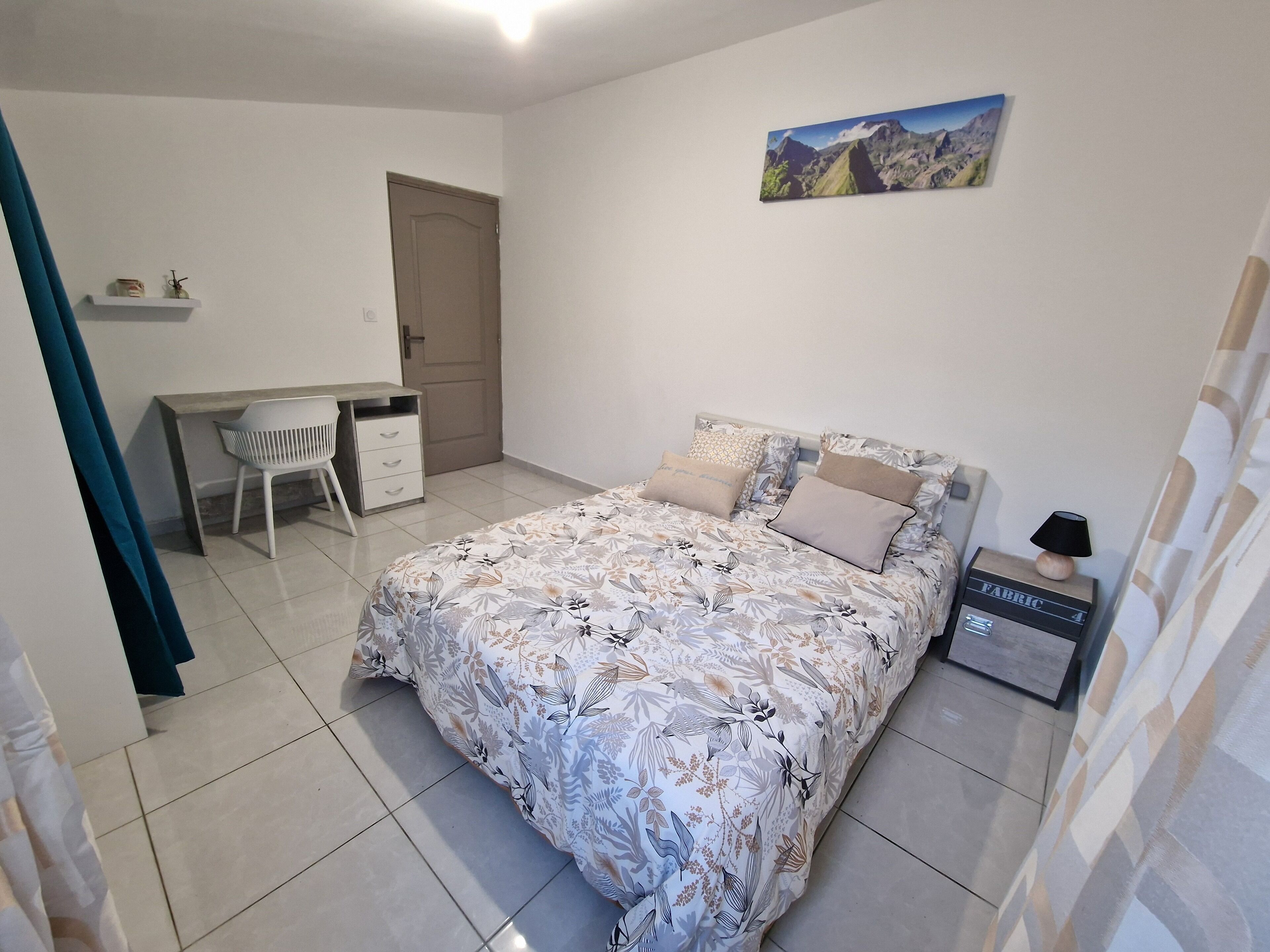 A bedroom with a bed, a desk, and a chair.
