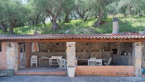 An outdoor patio area with brick walls, stone flooring, and white chairs. - Villa Delle Ginestre (Massarosa)