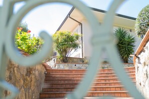 On voit un escalier menant à un bâtiment dont un côté est constitué d’un mur en pierre et l’autre d’une rambarde en métal.