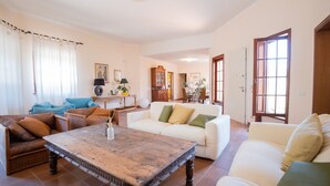 A spacious living room with a large wooden coffee table, two sofas, and a dining area in the background. - Villa Delle Ginestre (Massarosa)