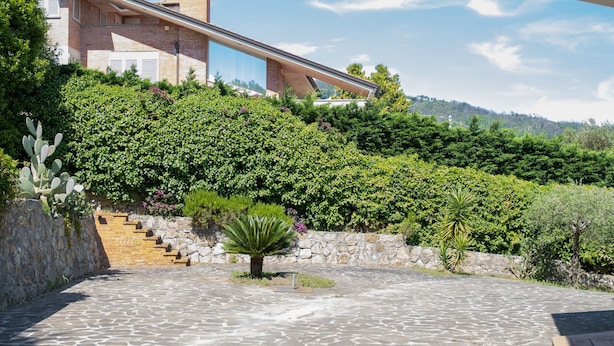A modern building with a stone staircase leading up to a glass entrance, surrounded by lush greenery. - Villa Delle Ginestre (Massarosa)