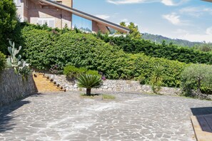 A modern building with a stone staircase leading up to a glass entrance, surrounded by lush greenery. - Villa Delle Ginestre (Massarosa)