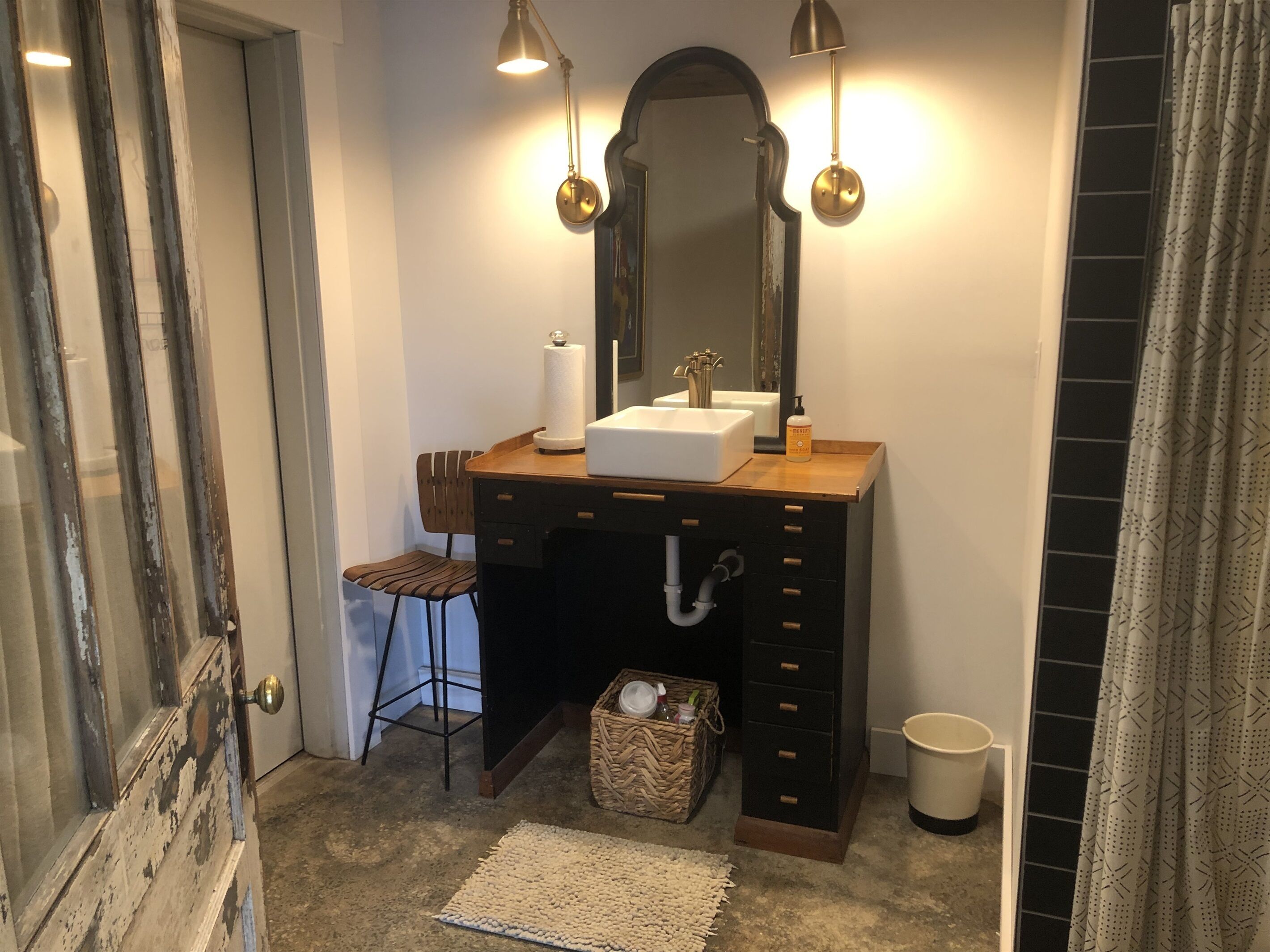 A bathroom with a wooden vanity, a mirror, a sink, and a stool.