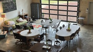 Una habitación amplia con un gran ventanal, un sofá verde, una mesa de comedor con sillas y un tablero de ajedrez.