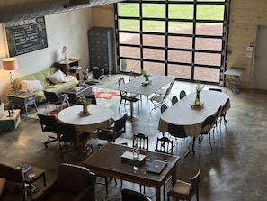 Una habitación amplia con un gran ventanal, un sofá verde, una mesa de comedor con sillas y un tablero de ajedrez.