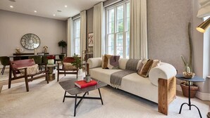 Un salon moderne comprenant un canapé, des fauteuils, une table basse et un coin repas avec des chaises et une table.