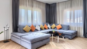 Ein modernes Wohnzimmer mit einem grauen Ecksofa, einem runden Couchtisch und einer Stehlampe.