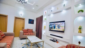 Ein modernes Wohnzimmer mit einer Couch, einem Couchtisch und einem an der Wand befestigten Fernseher.