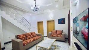 Ein modernes Wohnzimmer mit zwei Sofas, einem Couchtisch, einer Treppe und einem Fernseher.