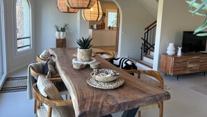 Un amplio comedor con una larga mesa de madera, asientos cómodos y lámparas colgantes.