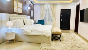 A modern bedroom with a bed, bedside table, lamp, and a fluffy rug. - Premium Luxury Apartment by Smart Home  (Lekki)