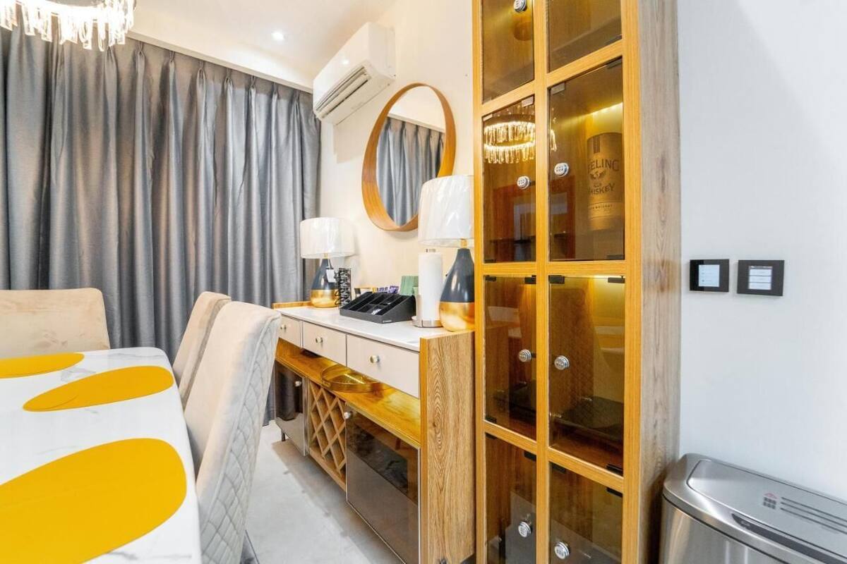 A hotel room with a bed, a vanity with a mirror, a minibar, and a wardrobe with glass doors.