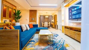 A modern living room with a blue sofa, a coffee table, and a TV. - Premium Luxury Apartment by Smart Home  (Lekki)
