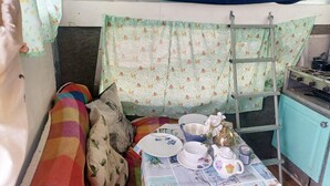 Una kitchenette compacta con una mesita, una silla y una cama litera encima.