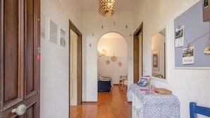 A hallway with wooden doors, a tiled floor, and a table with books and a basket. - Quiet Apartment by Wonderful Italy (Sanremo)