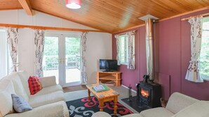 Una sala de estar acogedora con un sofá, televisor, mesa, chimenea y vistas al exterior.