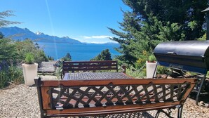 Eine Bank mit Grill und einem schönen Blick auf einen See und Berge.