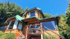 Eine Holzhütte mit einem grünen Dach, großen Fenstern und einem Balkon.