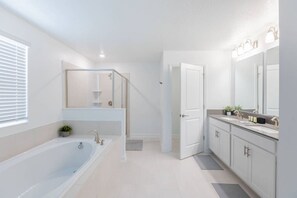 A modern bathroom with a freestanding bathtub, a glass-enclosed shower, and a vanity with a large mirror. - Cozy House w/ Game Room, Theater, Pool & More! (Davenport)