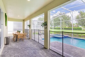 Un patio techado con piscina, una mesa con sillas y plantas en macetas.