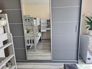 A bedroom with a bunk bed, a wardrobe, and a bedside table. - Cosy London Apartment in Waynflete Square (London)