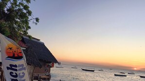 Een restaurant aan het strand met houten meubels en een rieten dak.