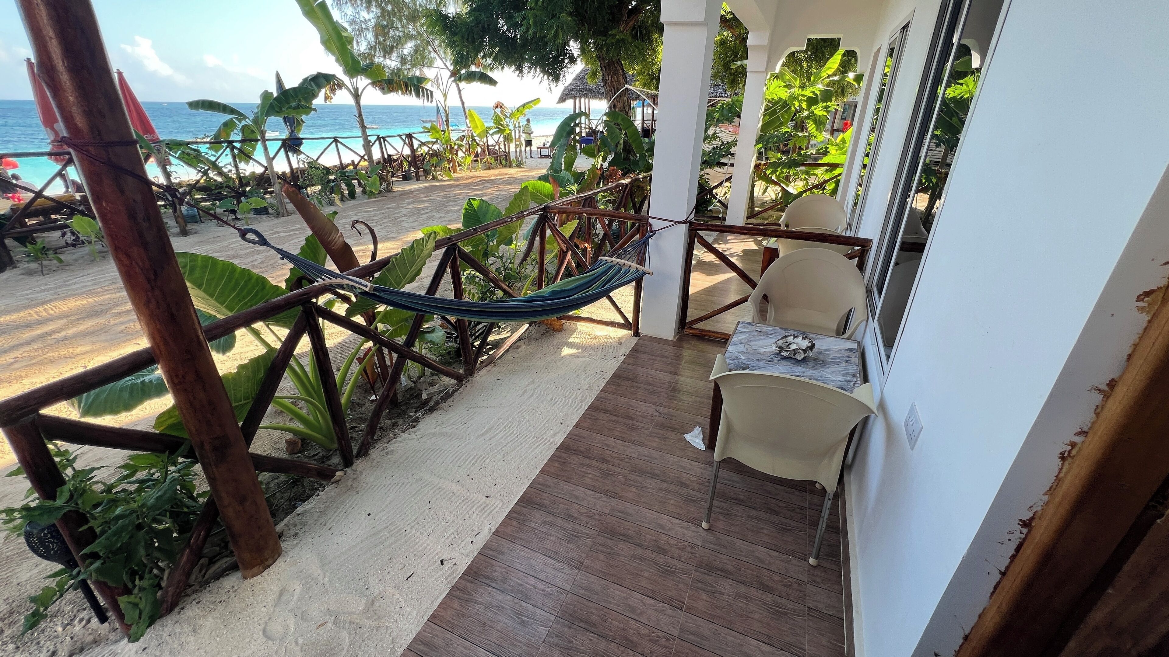 Ein Balkon mit Blick auf den Strand, einer Hängematte und einem Tisch mit Stühlen.