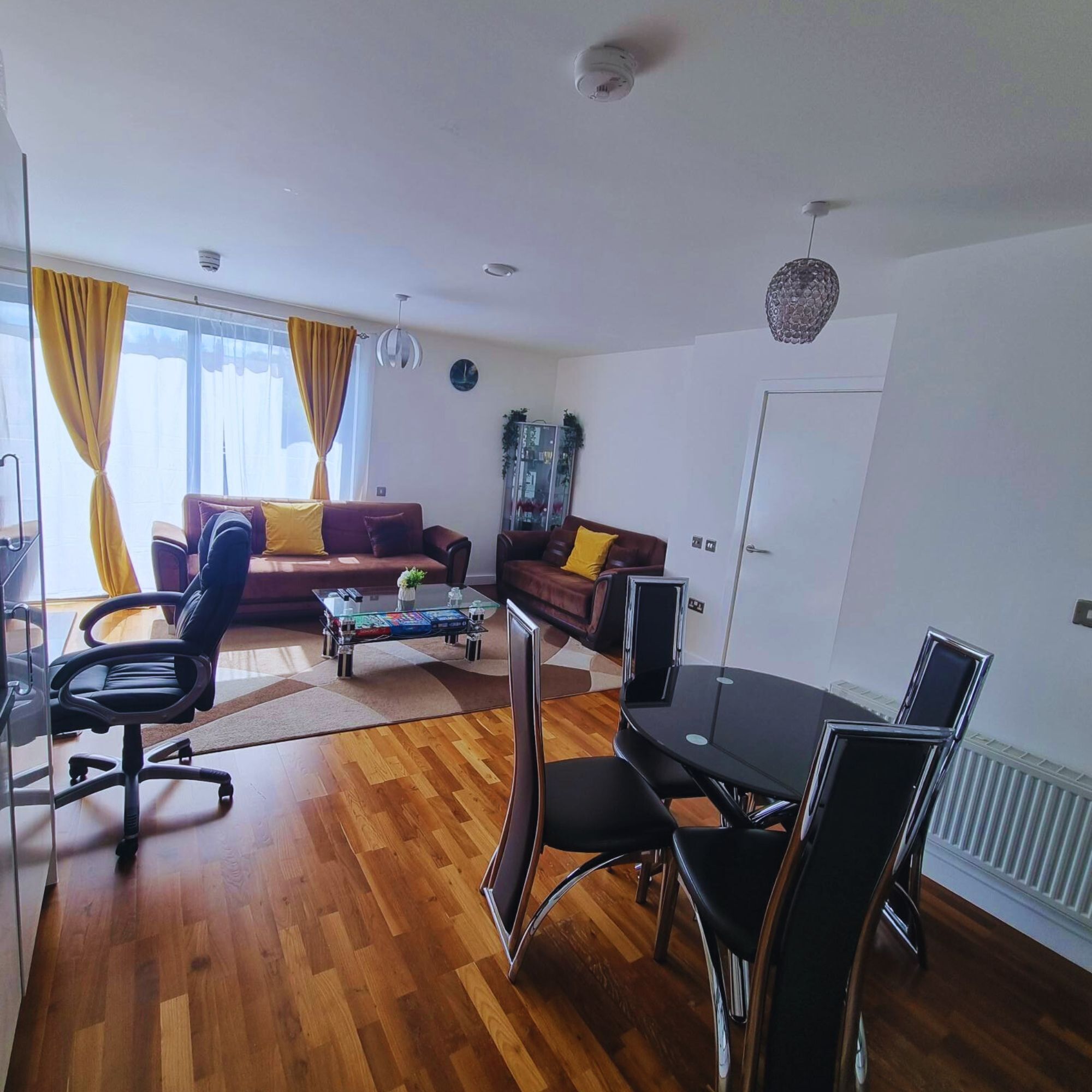Una sala de estar moderna con un sofá, sillones, una mesa de centro y una mesa de comedor con sillas.