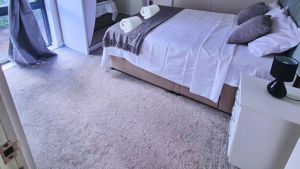 Una camera da letto con un letto, un armadio, uno specchio e una finestra con tende.