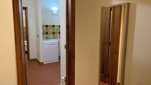 Käytävän päästä on pääsy keittiöön, jossa on pyykinpesukone, laatoitettu välitila ja puukehysovet.
