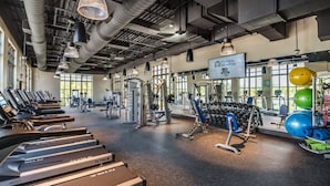 Une salle de sport équipée de tapis de course, d’appareils de musculation et de ballons d’exercice.