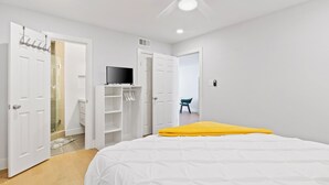 Een slaapkamer met een bed, een witte kledingkast en een televisie op een standaard.