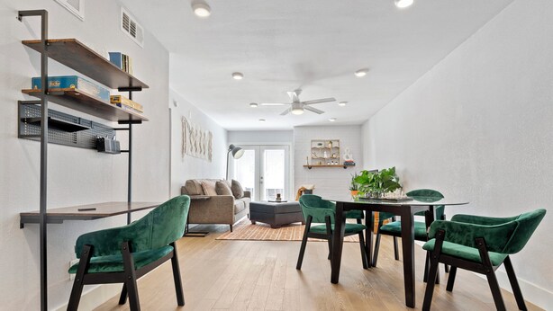 Een moderne woonkamer met een eethoek, met een bank, stoelen, een tafel en inbouwkasten.