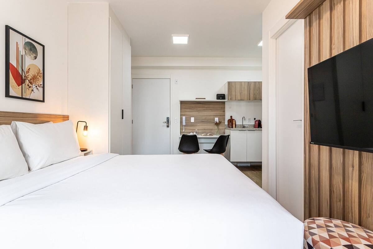 Une chambre d’hôtel équipée d’un lit, d’une télévision, d’un bureau et d’une kitchenette.