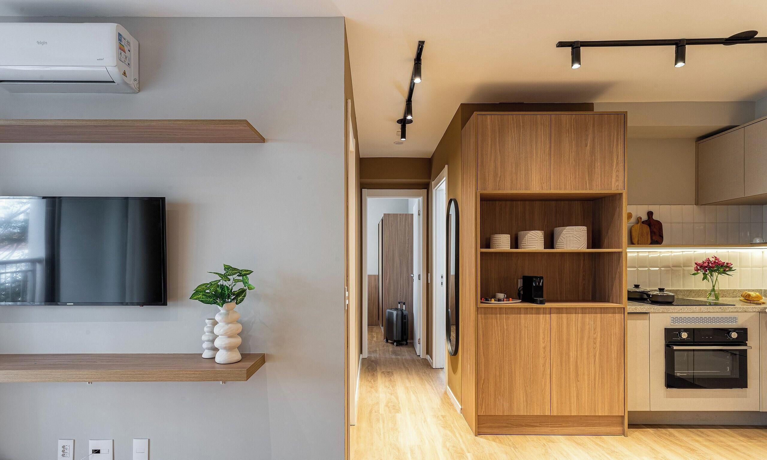 A modern kitchen with wooden cabinets, a built-in oven, and a TV mounted on the wall.