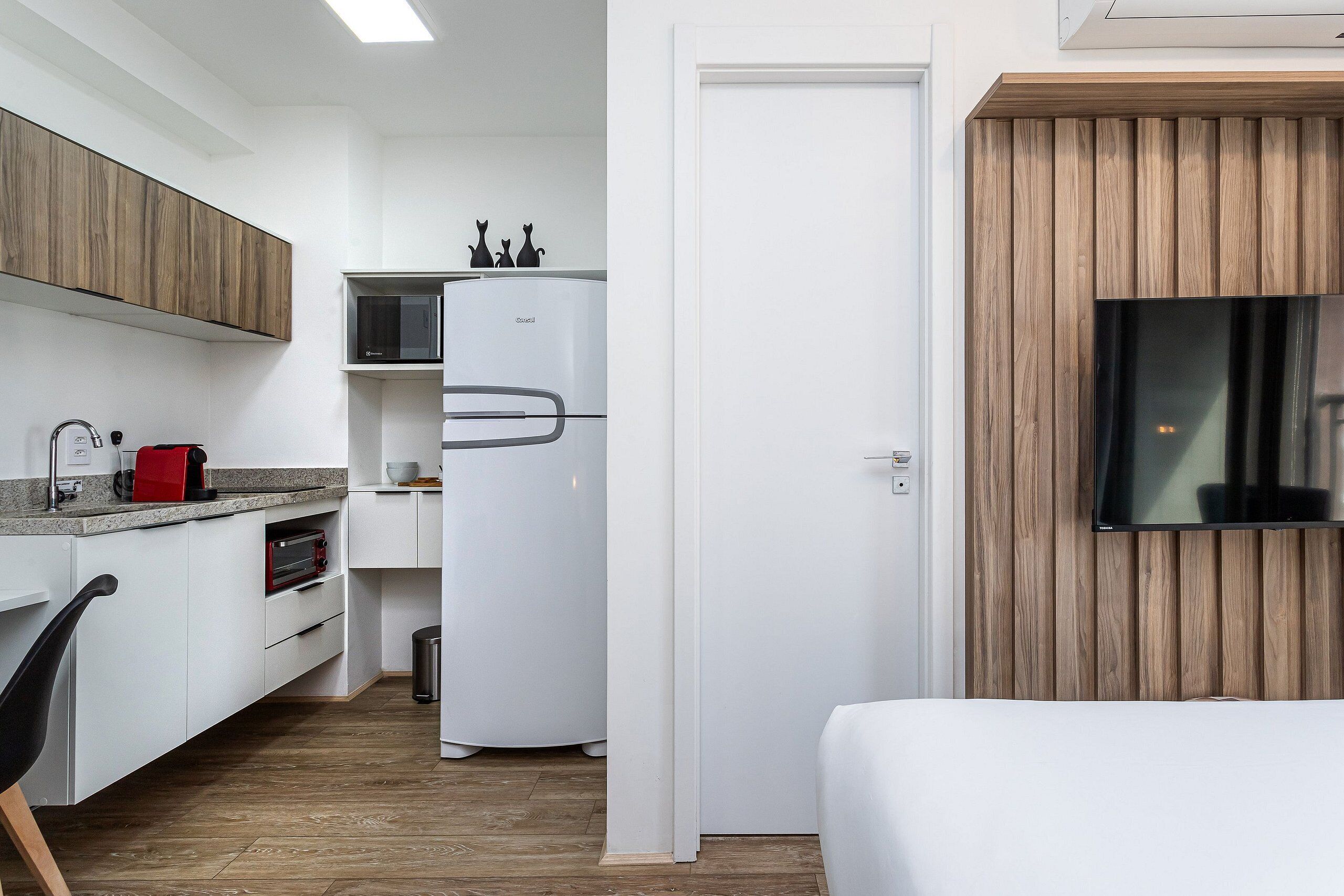 A compact kitchen with white cabinetry, a built-in microwave, and a refrigerator.
