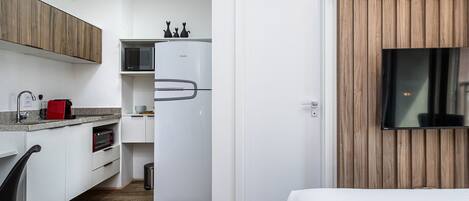 A compact kitchen with white cabinetry, a built-in microwave, and a refrigerator.
