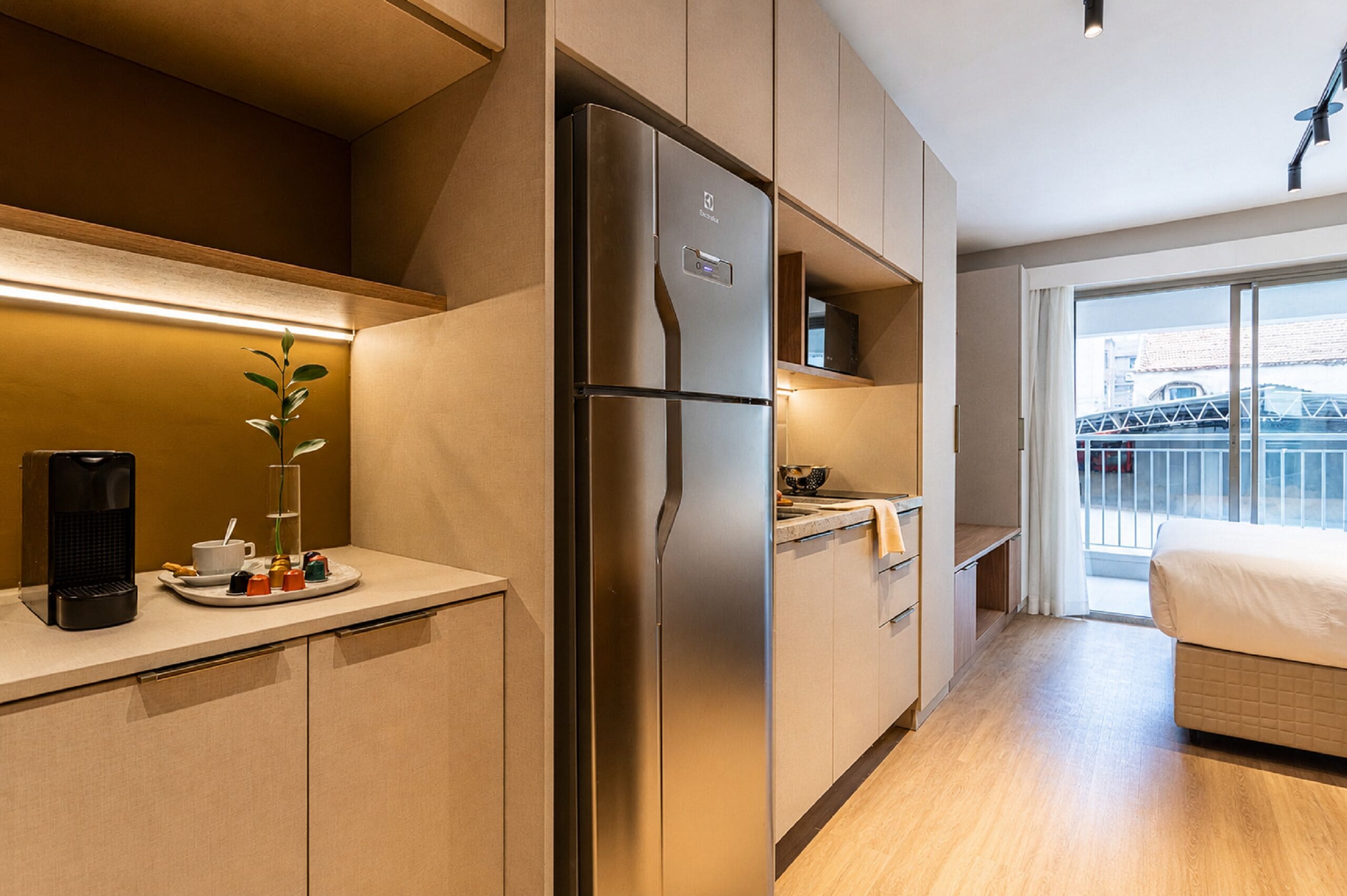 Una cocina moderna con refrigerador integrado, una cafetera y un comedor con vistas al exterior.