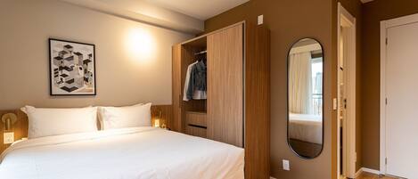A bedroom with a bed, a wardrobe, a mirror, and a wall-mounted light fixture.