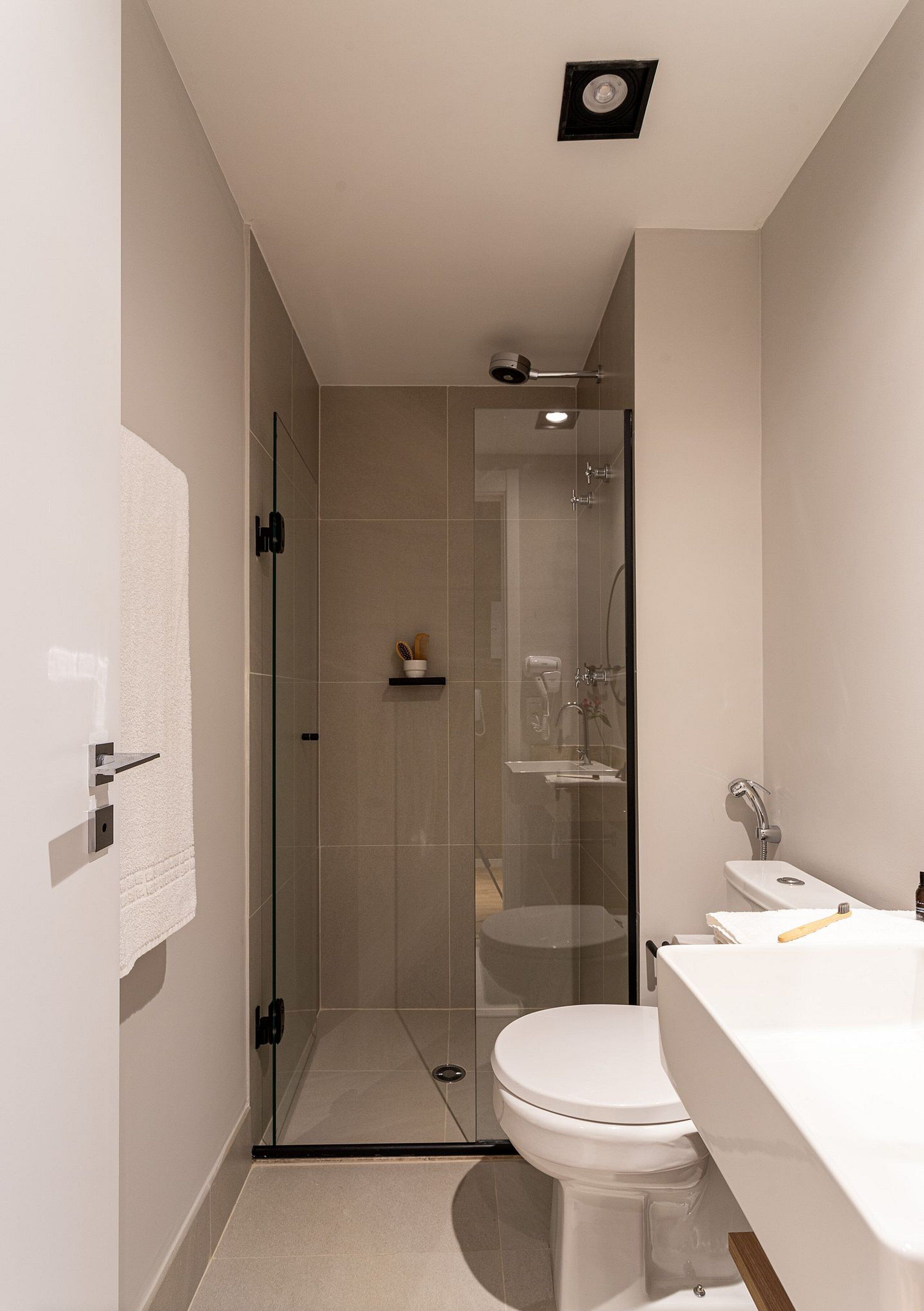 A modern bathroom with a glass-enclosed shower, a white toilet, and a sink with a mirror.