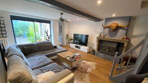 Una sala de estar moderna con un sofá seccional, un televisor de pantalla plana, una chimenea y una escalera.
